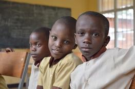 Foto på tre barn som sitter i ett klassrum i Rwanda